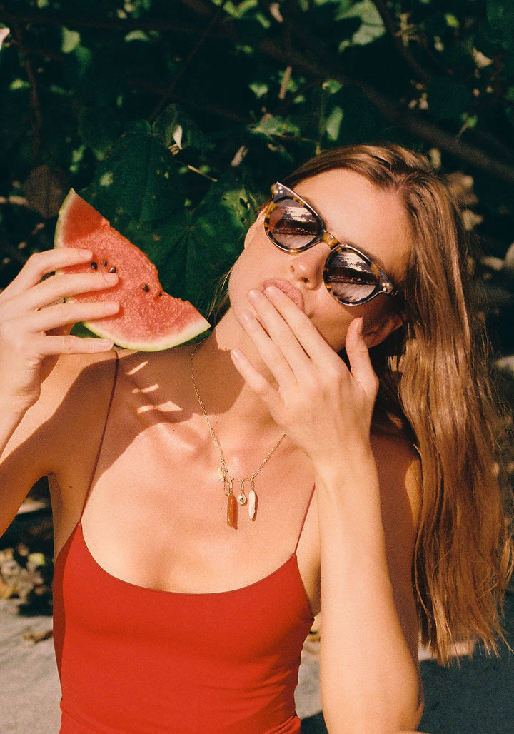Woman eating a watermelon slice outdoors with sunglasses on