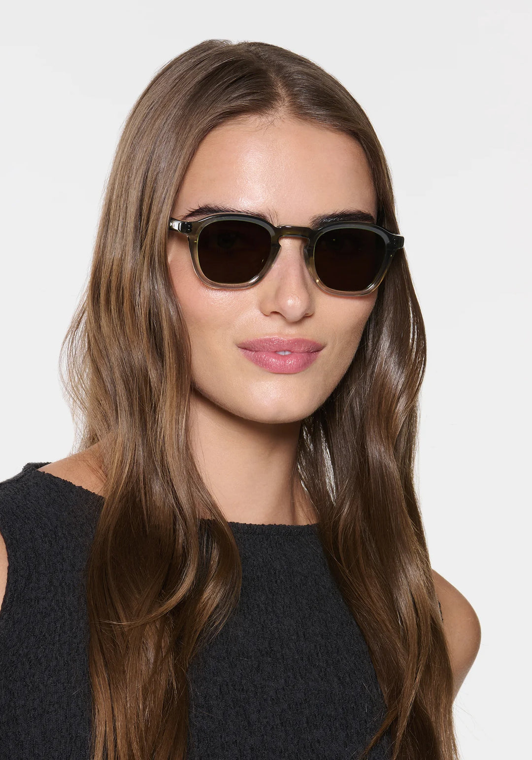 Woman wearing dark sunglasses against a plain background
