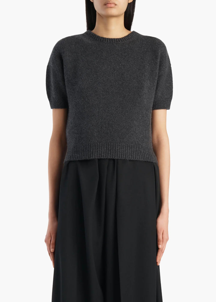 Person wearing a dark gray sweater and black pants on a white background