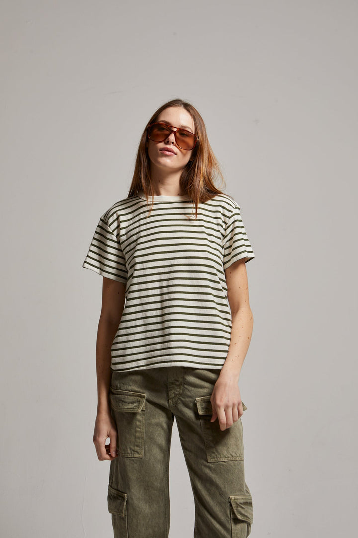 Woman wearing a striped shirt and cargo pants against a plain background