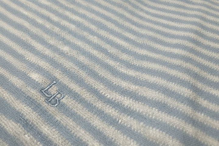 Close-up of a fabric with blue and white stripes and a logo in the corner.