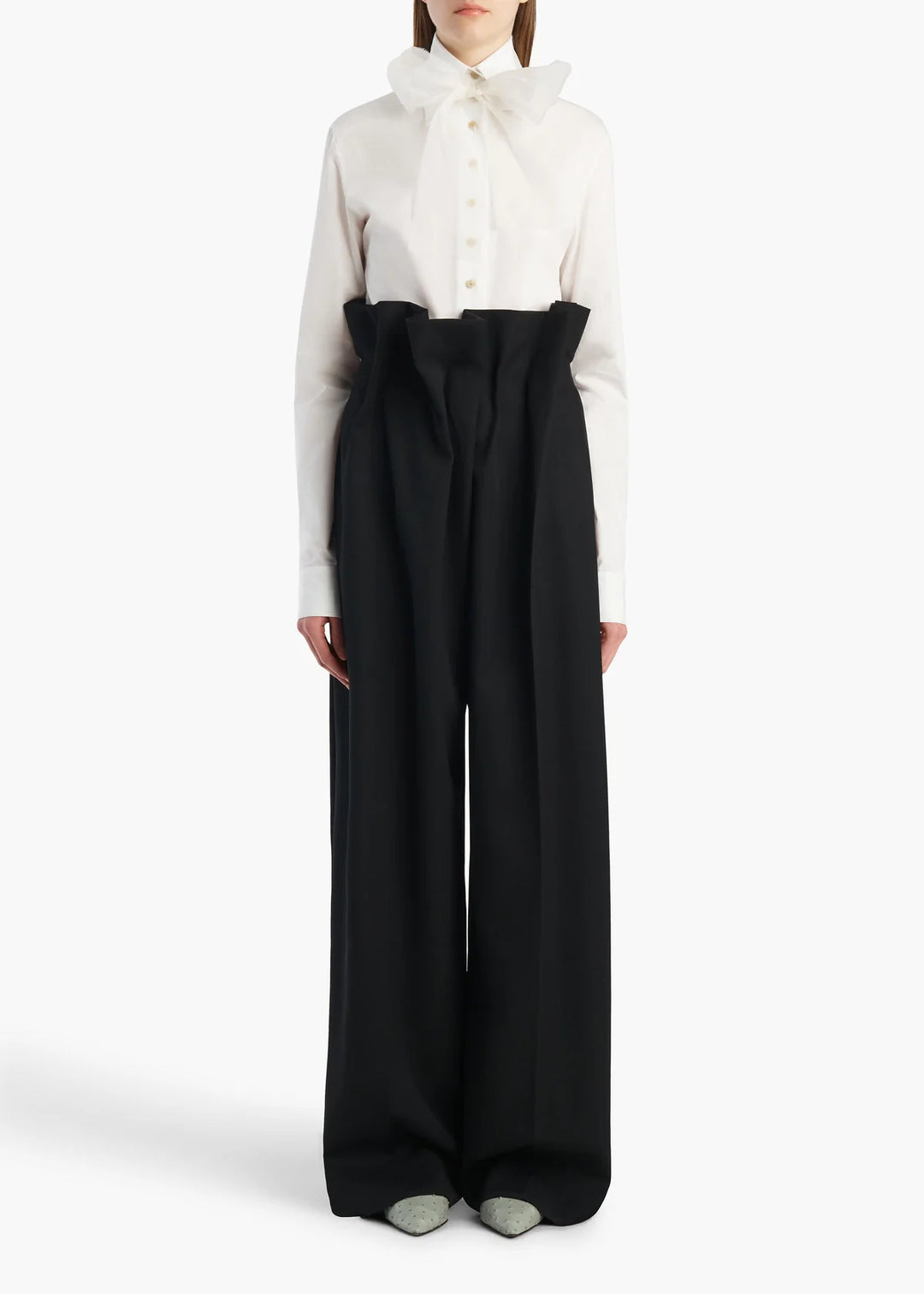 Person wearing a white shirt and black wide-leg pants on a white background