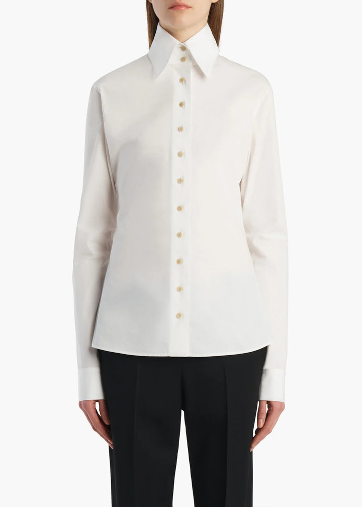 A model wearing a white long-sleeve button-down shirt with a pointed collar and black trousers, shown from the neck down against a plain white background.