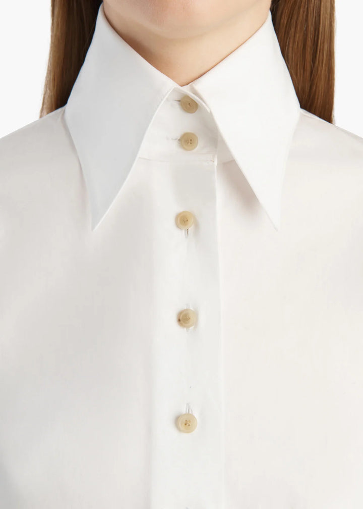 Close-up of a white collared button-up shirt worn by a model, showing the collar, front placket, and light beige buttons.