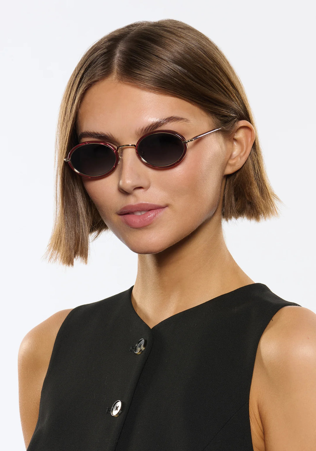 Woman wearing round sunglasses with a plain background