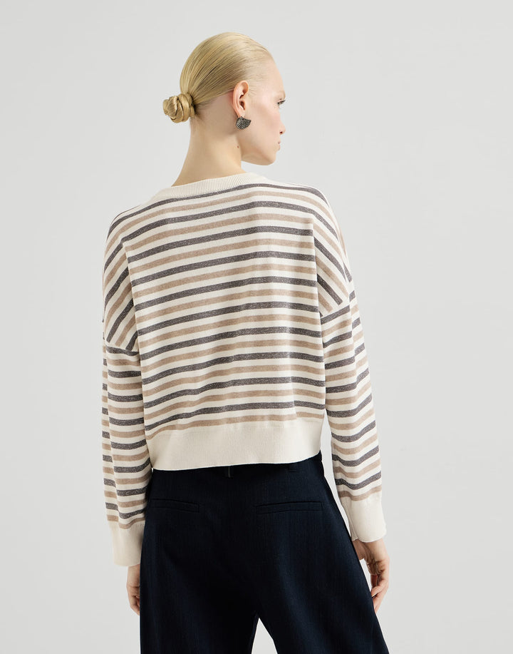 A woman shown from the back wearing a cropped long-sleeve knit sweater with horizontal beige, cream, and taupe stripes, paired with dark navy pants, against a light gray studio background.