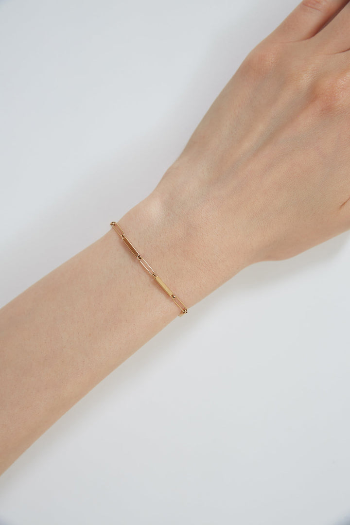 Rose gold bracelet on a wrist against a white background