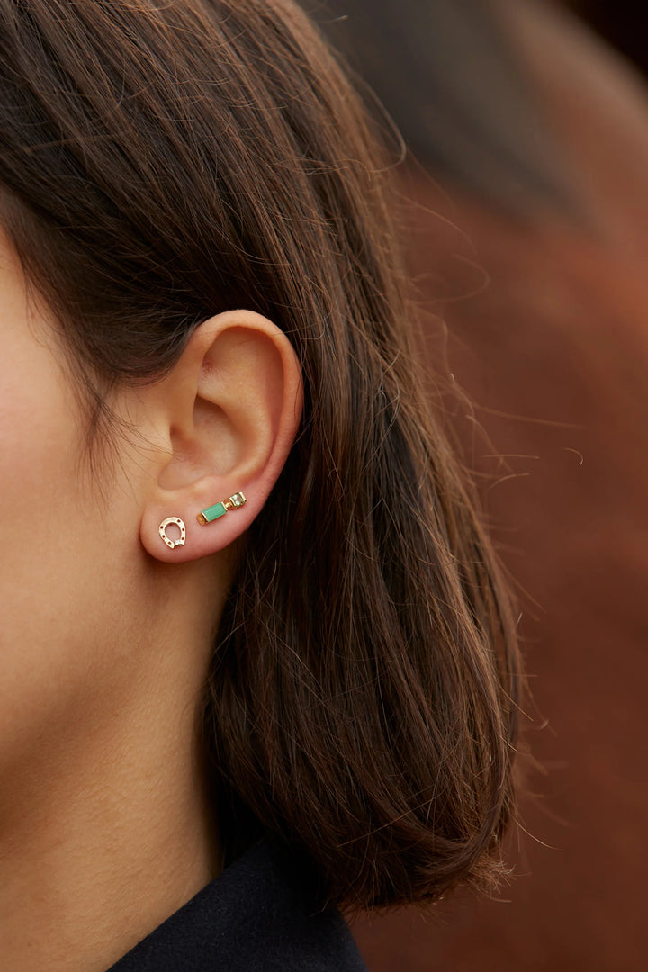 Close-up of a person wearing two earrings with a blurred background