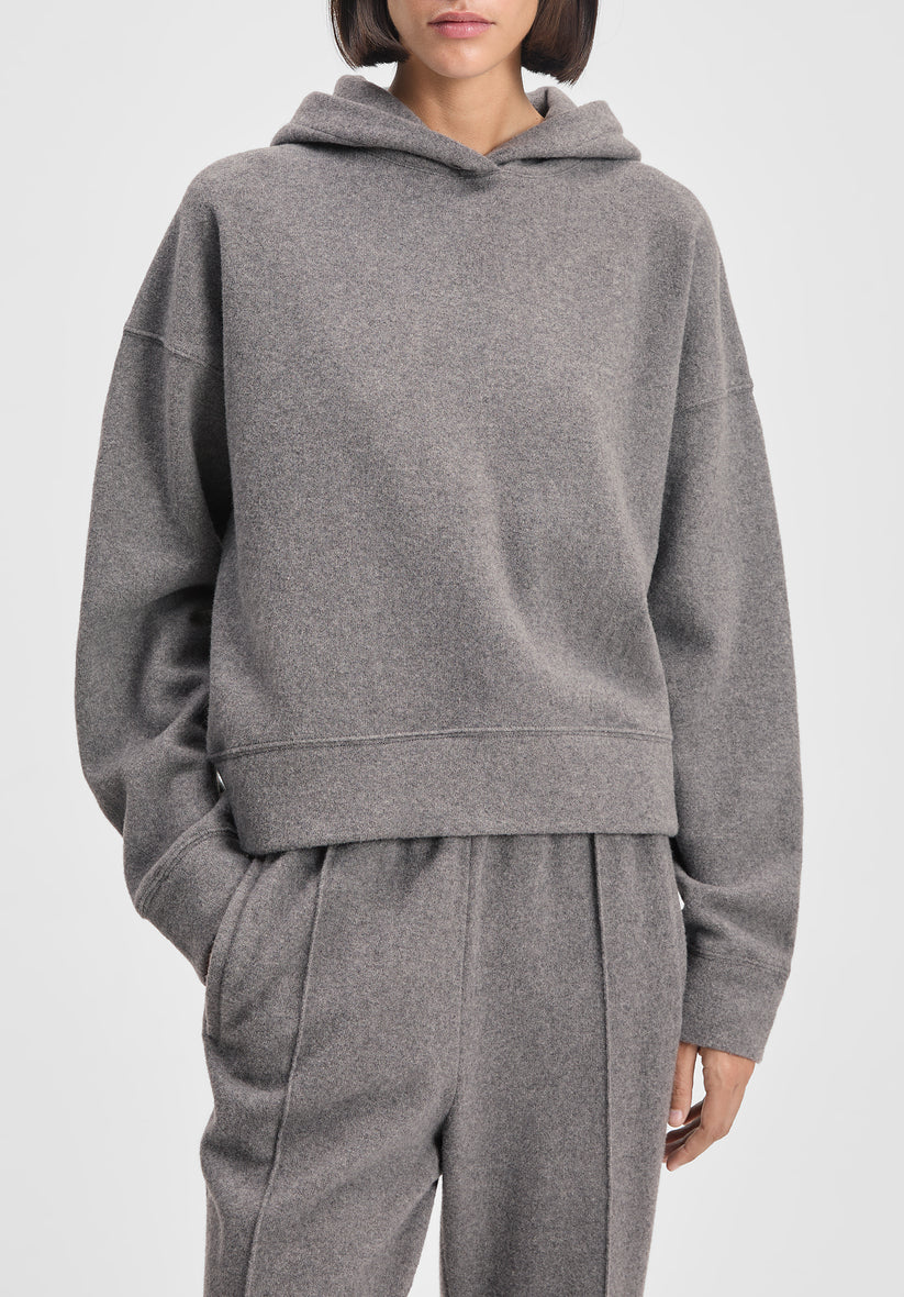 Person wearing a gray hoodie and pants on a white background