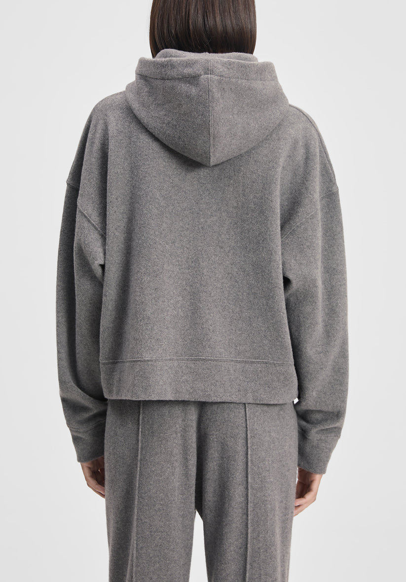 Person wearing a gray hoodie and pants on a white background