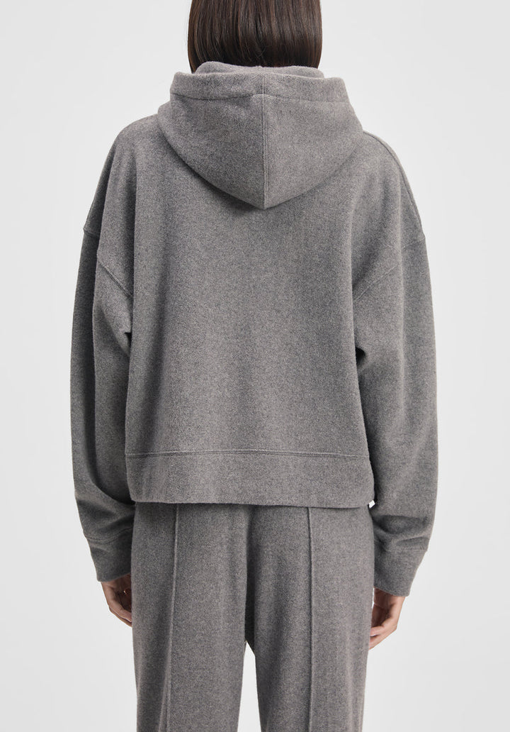 Person wearing a gray hoodie and pants on a white background