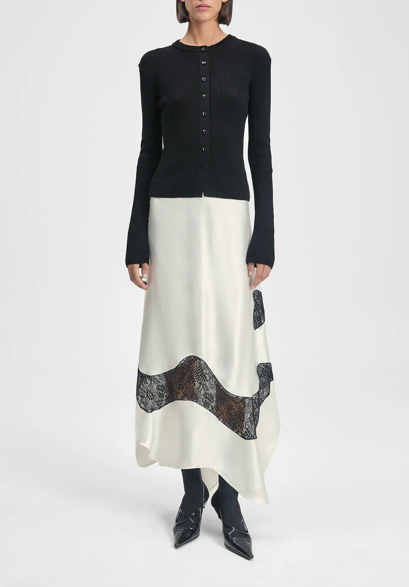 Person wearing a black long-sleeve top and white skirt with lace details on a white background