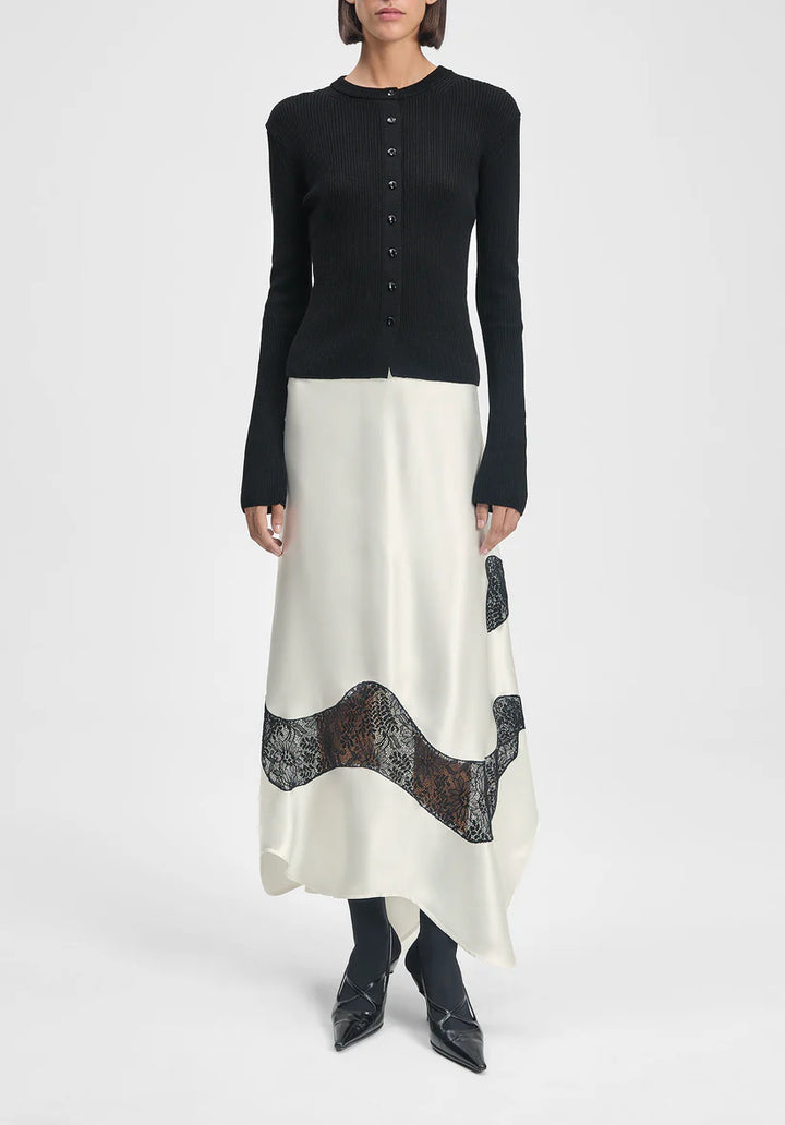 Person wearing a black long-sleeve top and white skirt with lace details on a white background