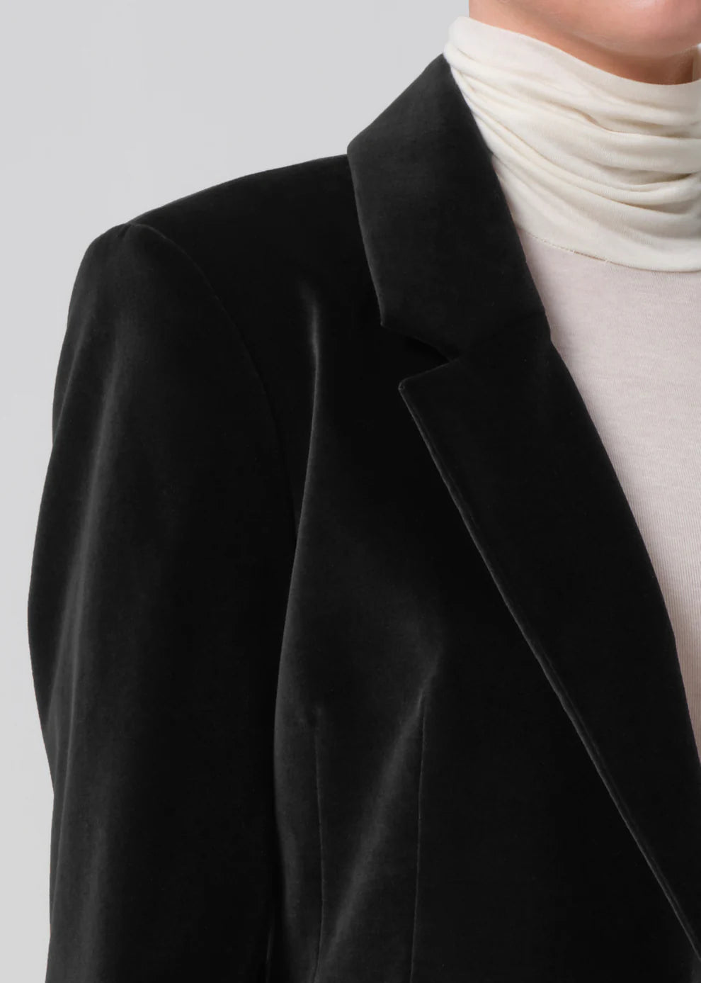 Black blazer over a white turtleneck on a plain background