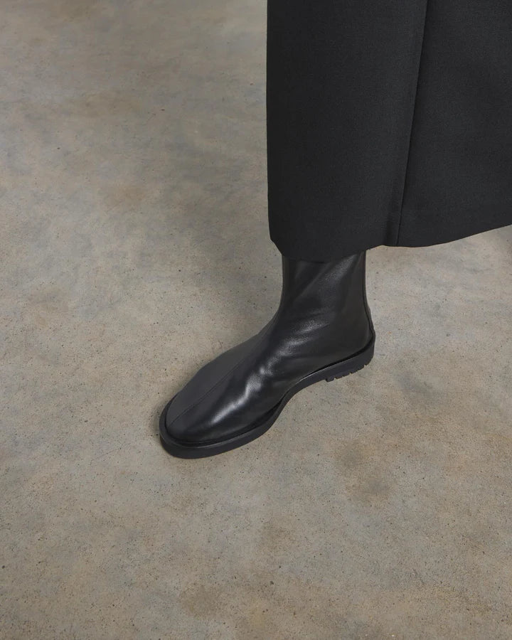Black leather boot on a neutral floor