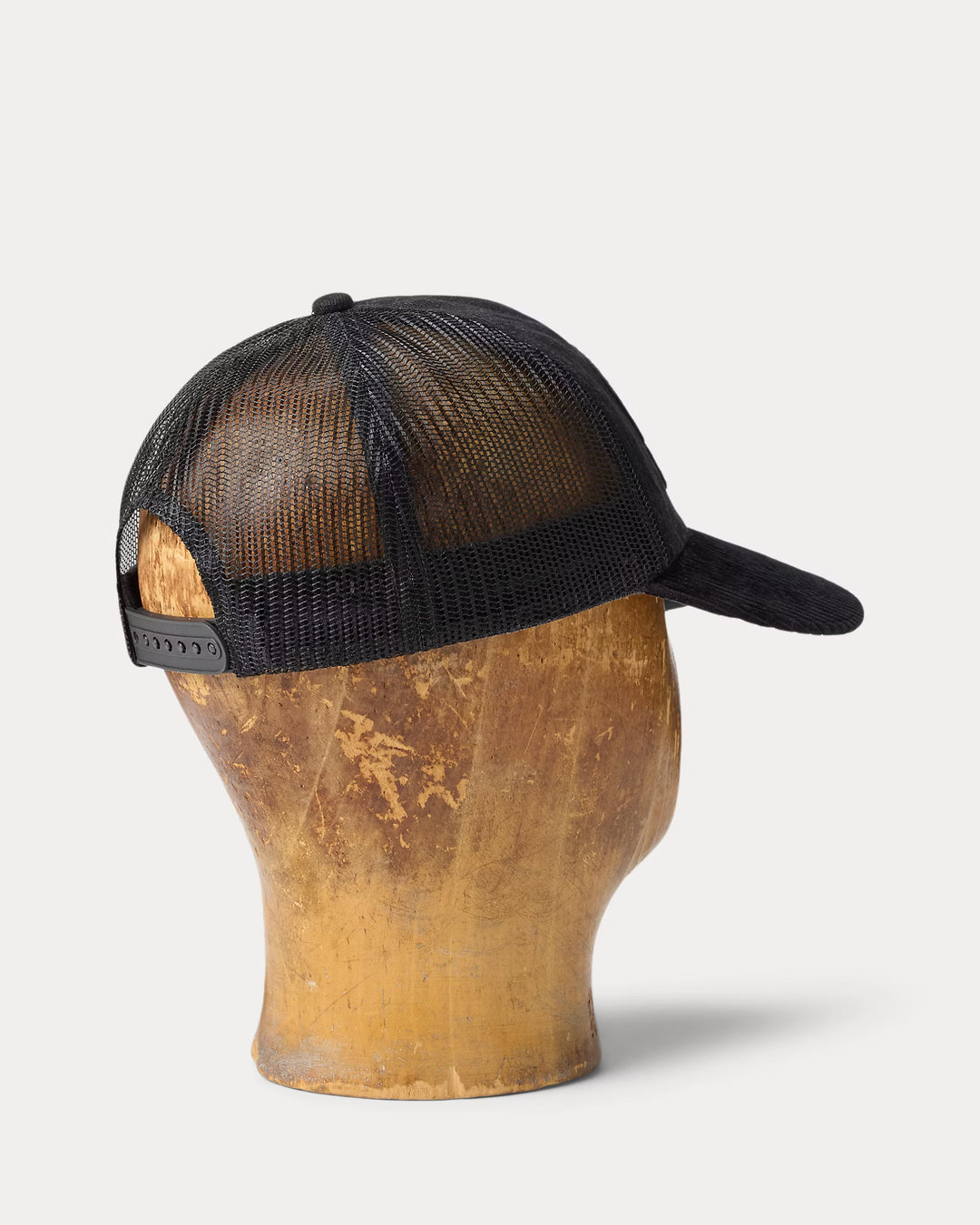 Black mesh cap on a wooden mannequin head against a light gray background