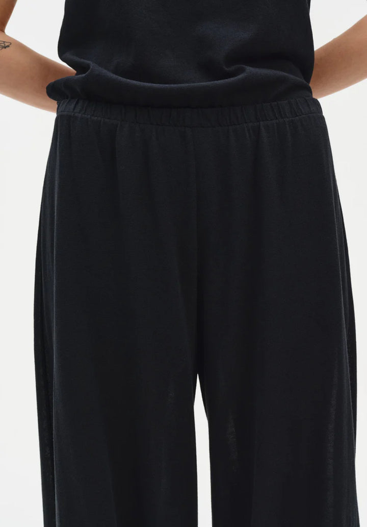Black pants worn by a person on a white background