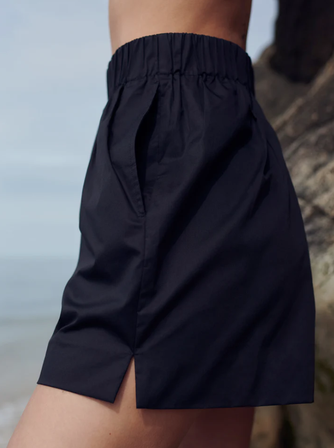 Black shorts worn by a person with a blurred natural background