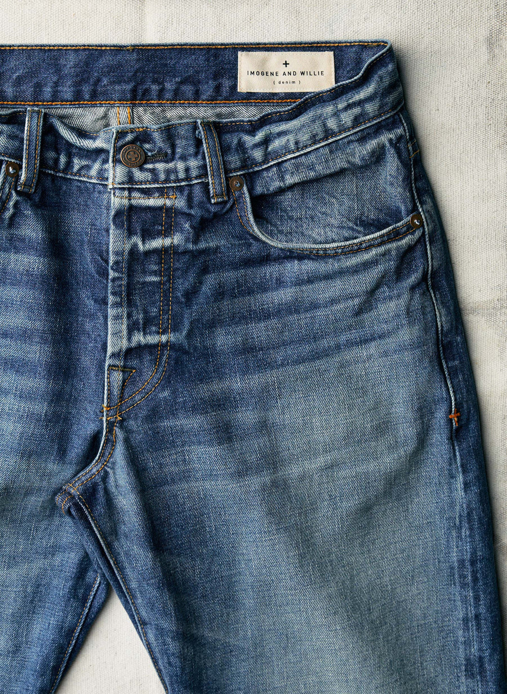Blue jeans with a brand label on a light gray background