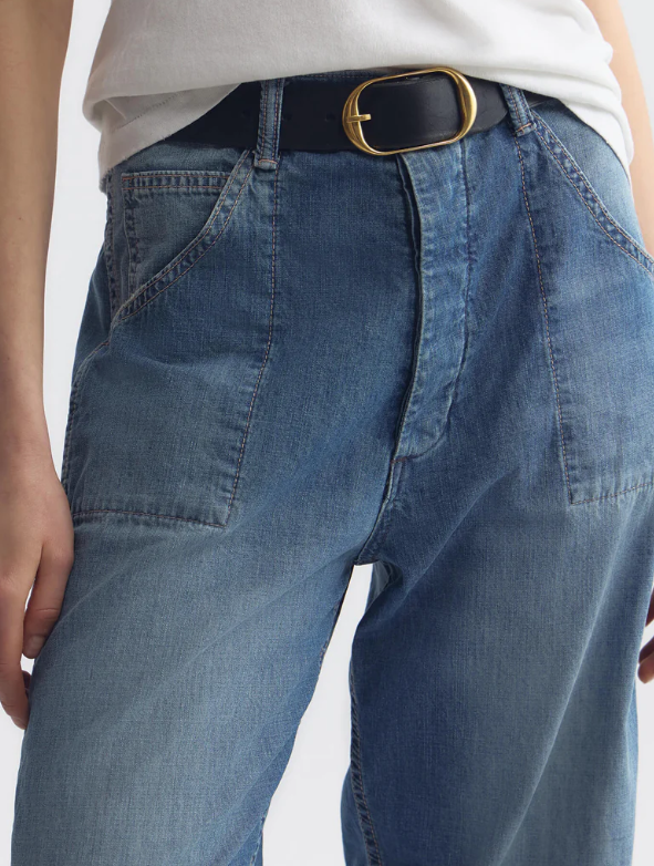 Blue jeans with a gold belt buckle on a white background