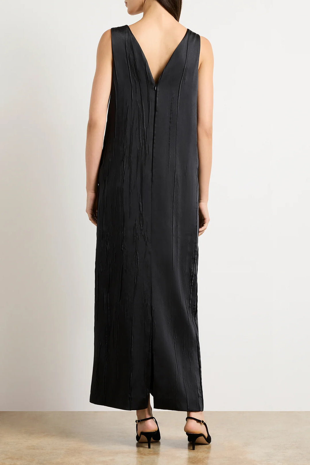 Black sleeveless dress worn by a person on a plain background