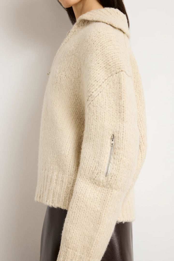 Beige knitted jacket with a zipper on a plain background