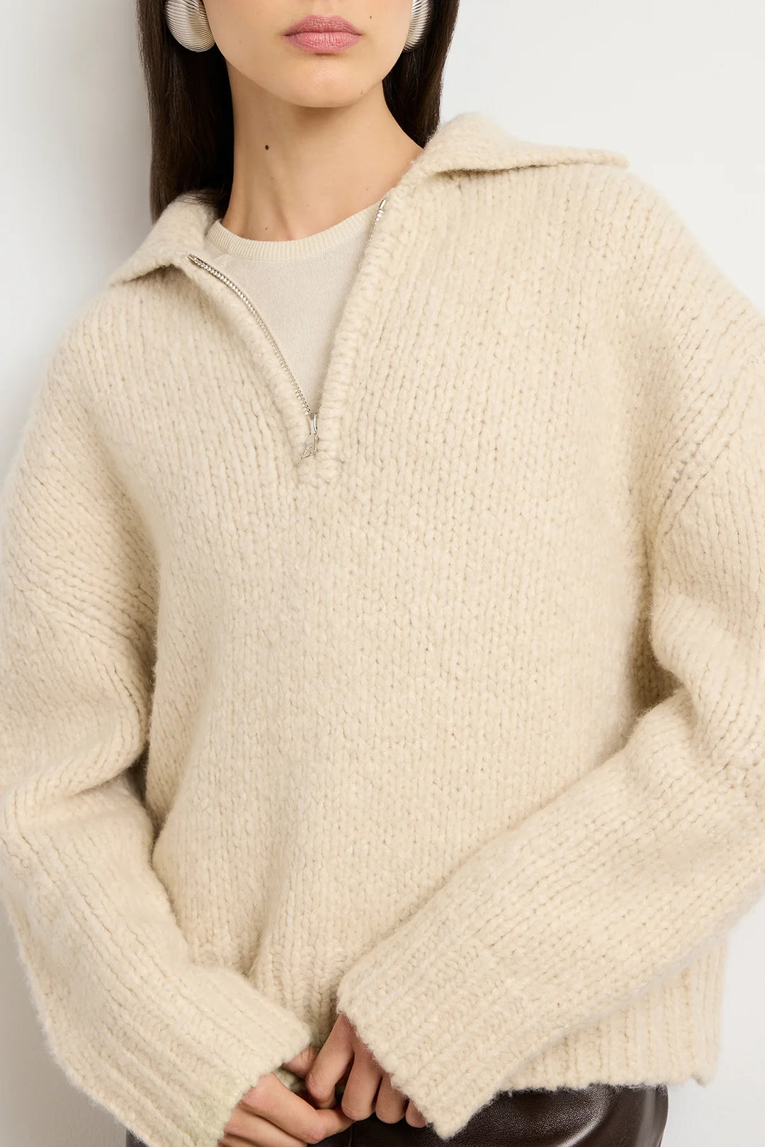 Person wearing a beige hooded sweater against a plain background