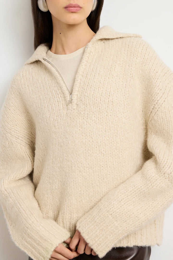 Person wearing a beige hooded sweater against a plain background