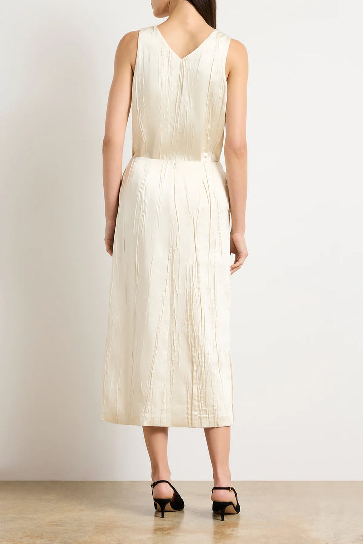 Woman wearing a white pleated dress against a plain background