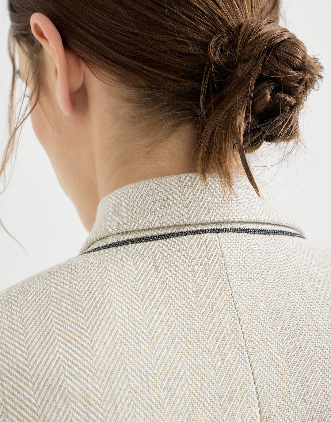 Close-up of a person wearing a textured beige blazer with a white background