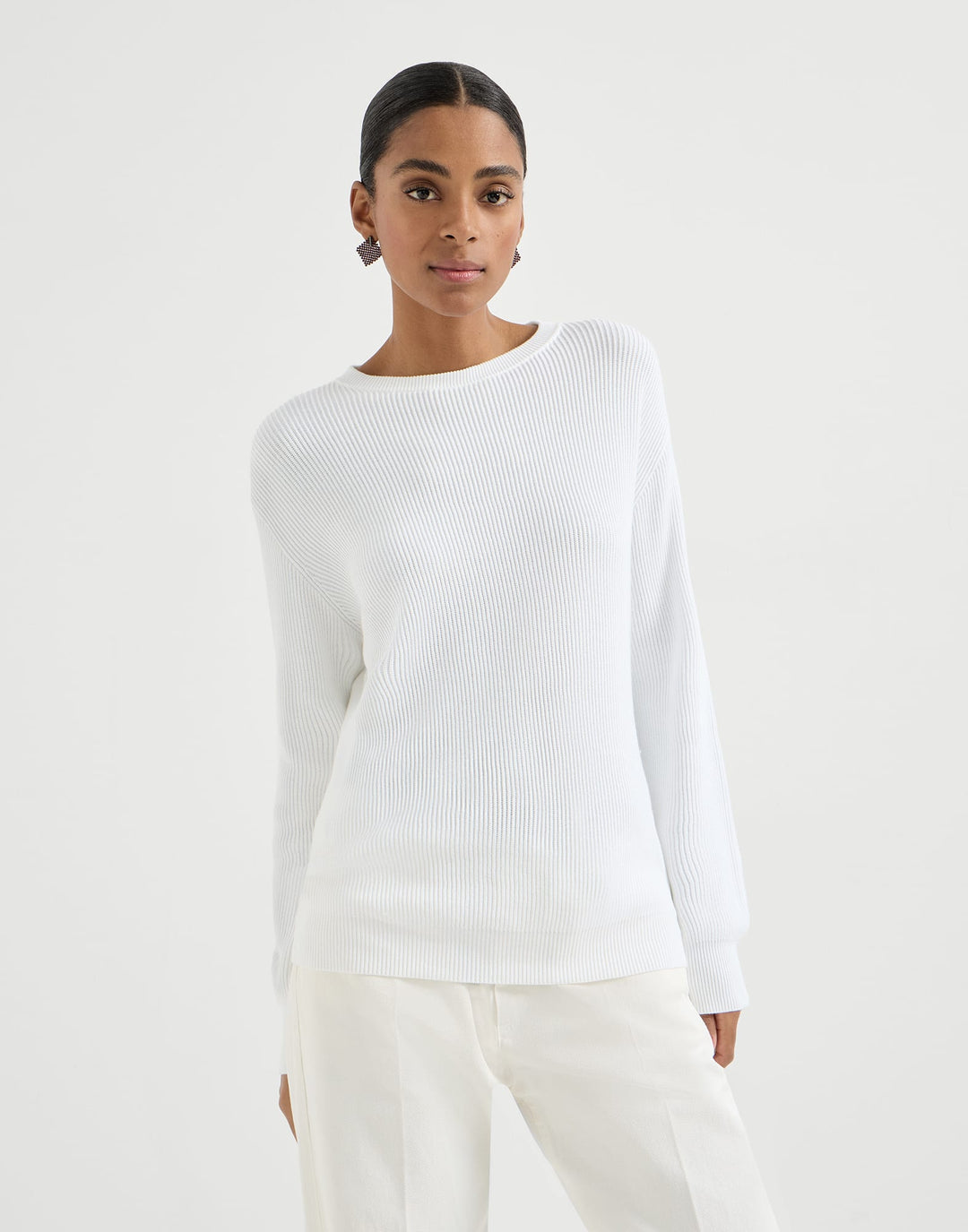 Woman wearing a white ribbed sweater and pants on a light gray background