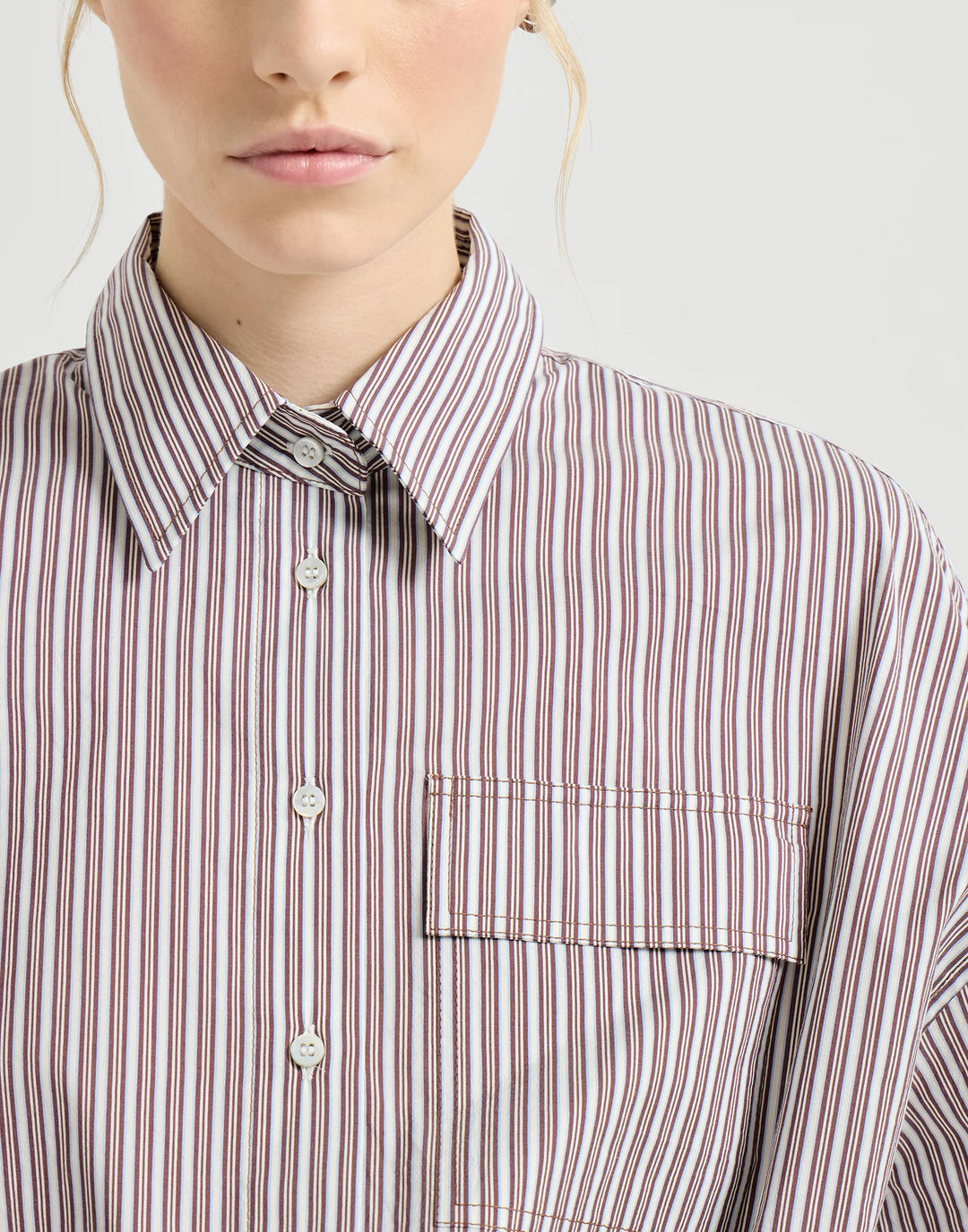 Close-up of a person wearing a striped shirt with a neutral background
