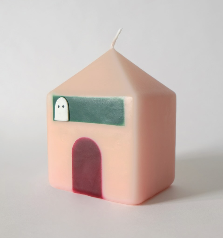 Candle shaped like a house with a ghost design on a light gray background