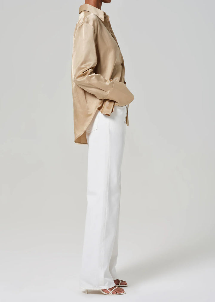 Person wearing a beige shirt and white pants on a plain background