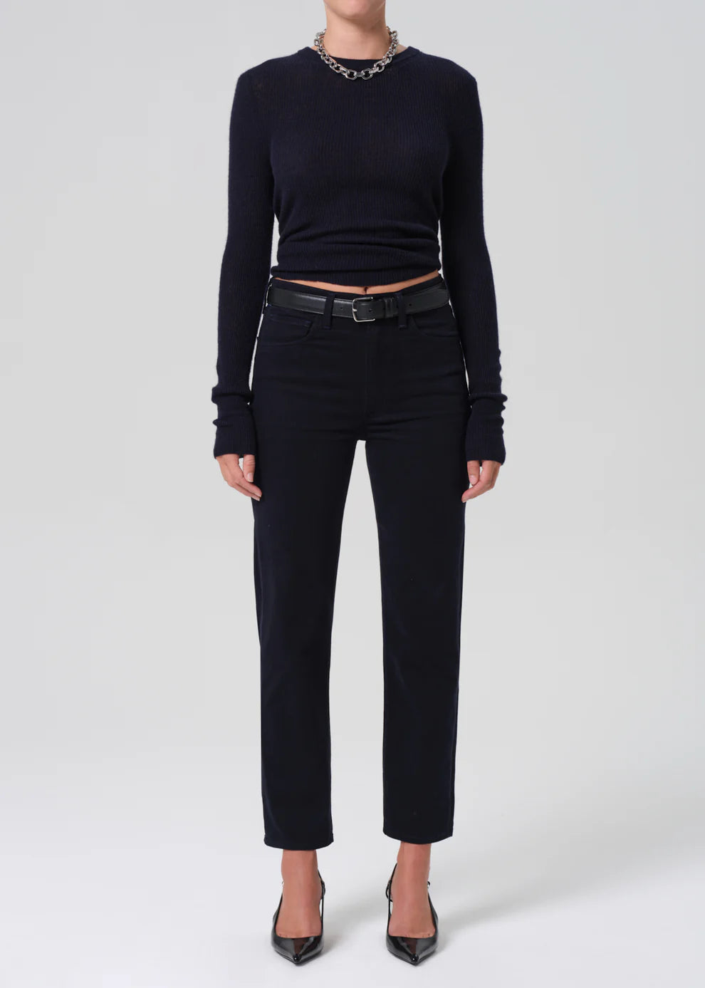 Person wearing a black long-sleeve top and black pants on a white background