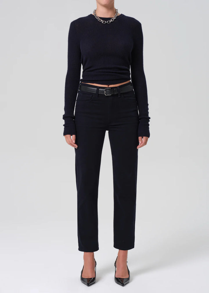 Person wearing a black long-sleeve top and black pants on a white background