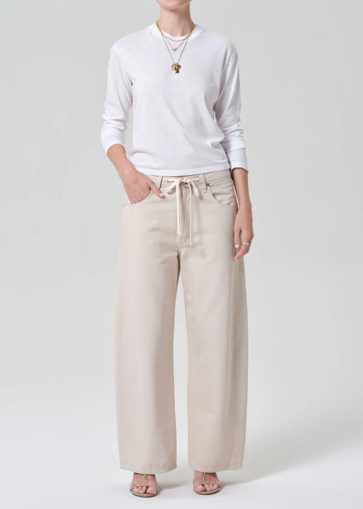 Person wearing a white sweater and beige pants on a plain background