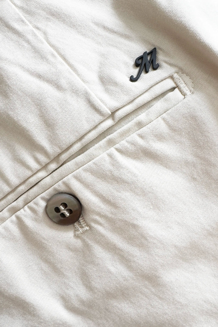 Close-up of a beige fabric with a button and monogram on a white background