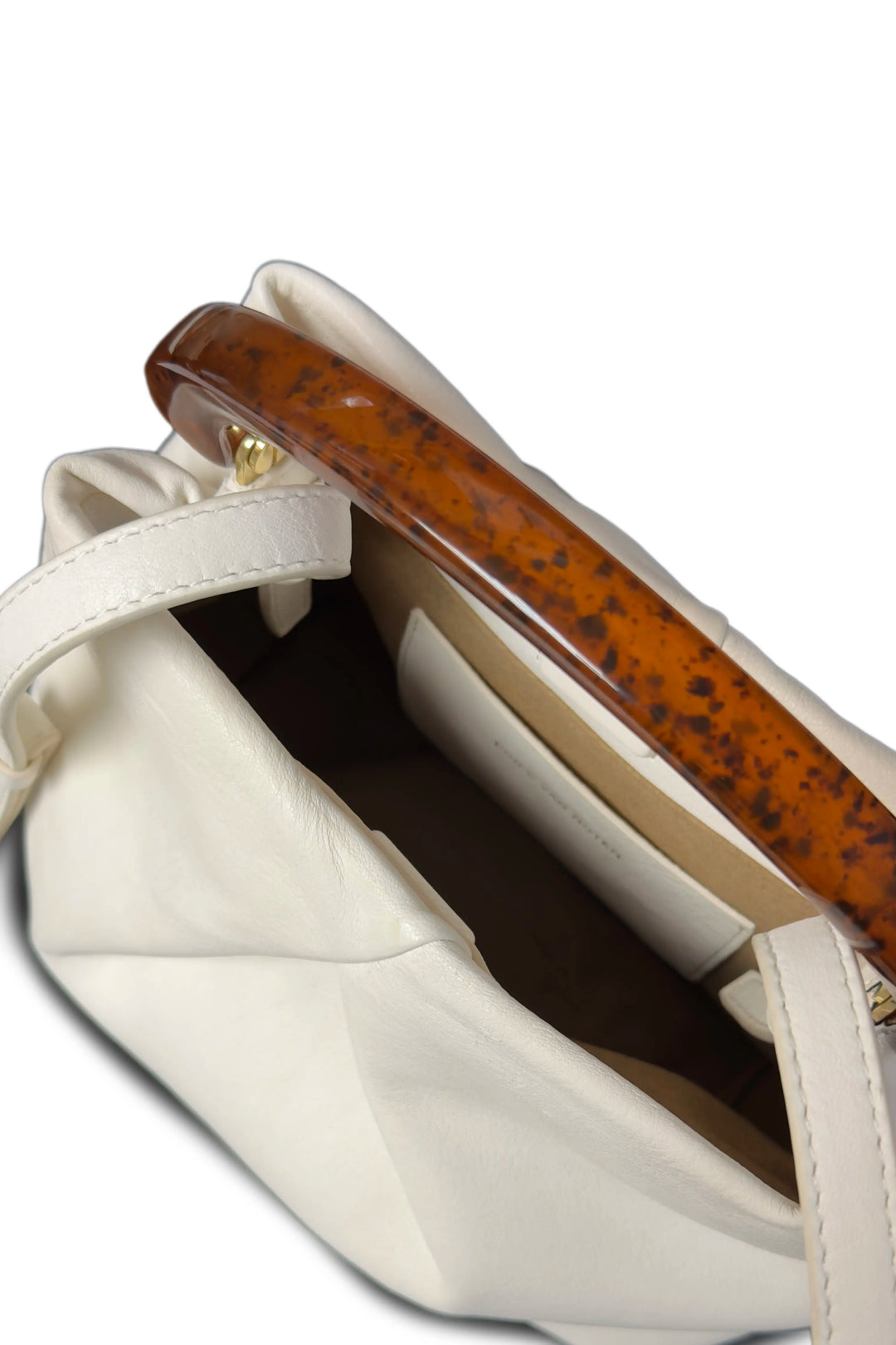 Close-up of a beige handbag with a tortoiseshell handle on a white background