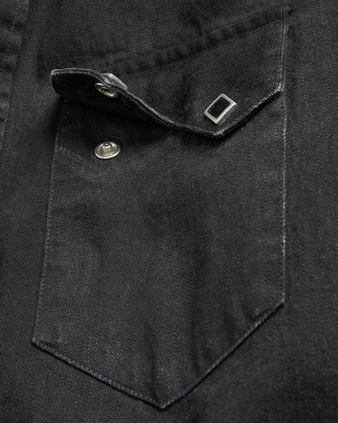 Close-up of a black shirt pocket with a button and flap.