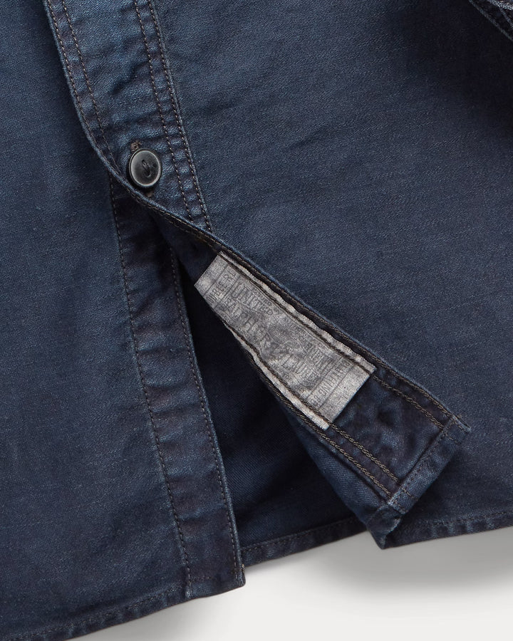 Close-up of a blue denim shirt with a button and gray lining on a white background