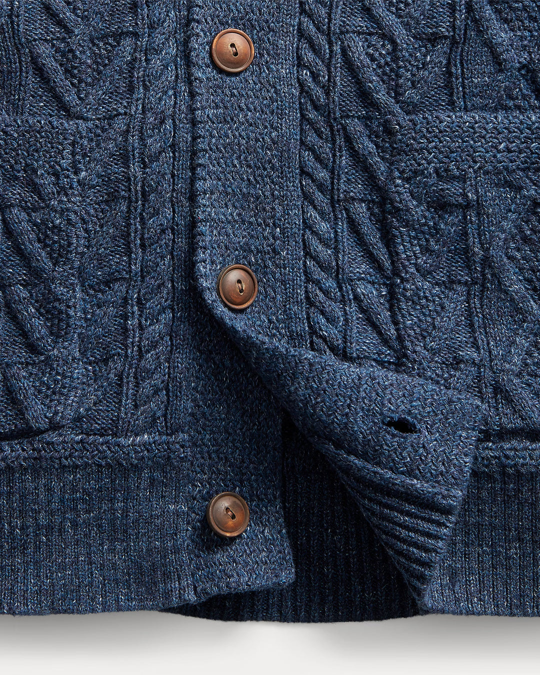 Close-up of a blue knitted cardigan with brown buttons on a light gray background