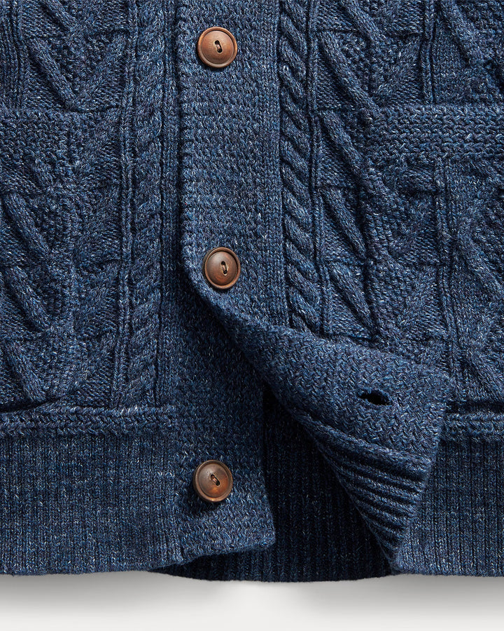 Close-up of a blue knitted cardigan with brown buttons on a light gray background
