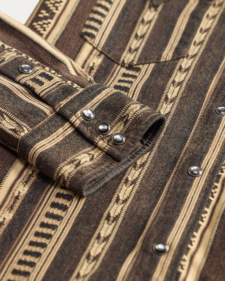 Close-up of a brown and beige patterned fabric with buttons and stitching details.