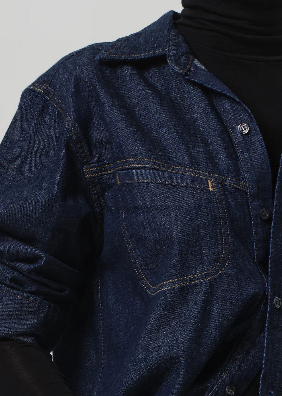 Close-up of a dark blue denim shirt with a plain background