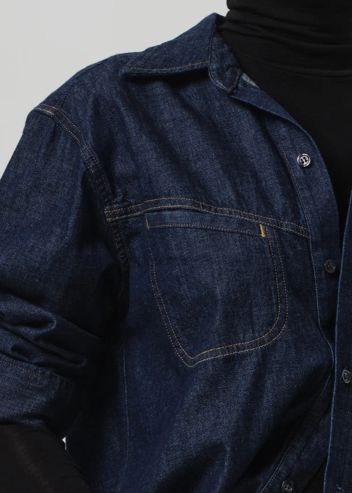 Close-up of a dark blue denim shirt with a plain background