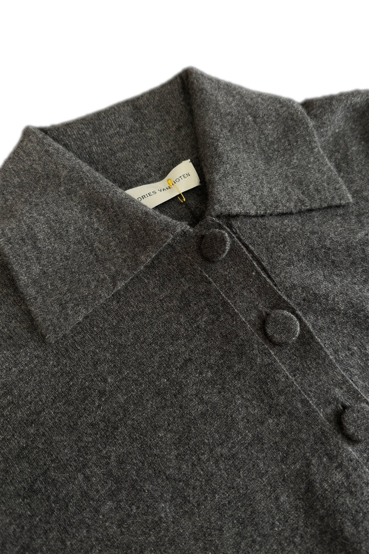 Close-up of a dark gray coat with buttons and a visible brand label on a white background