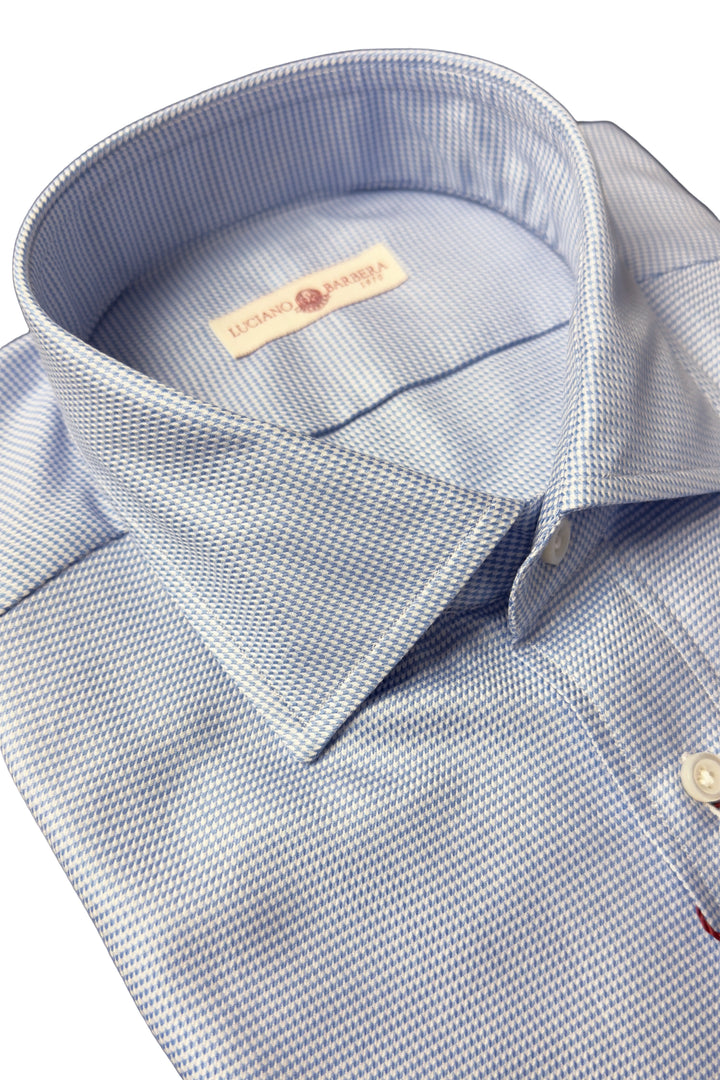 Close-up of a light blue and white micro-patterned dress shirt collar with a visible neck label reading 'DUNAGE BRAND'.