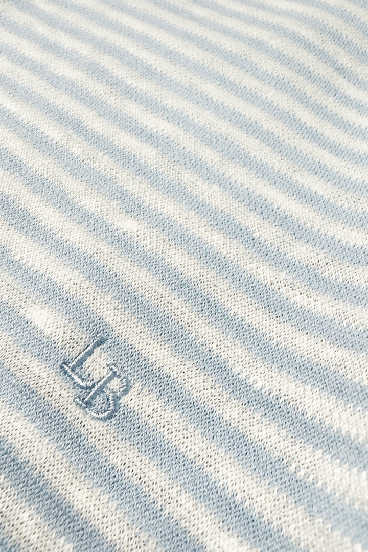 Close-up of a light blue and white striped fabric with a logo in the corner.