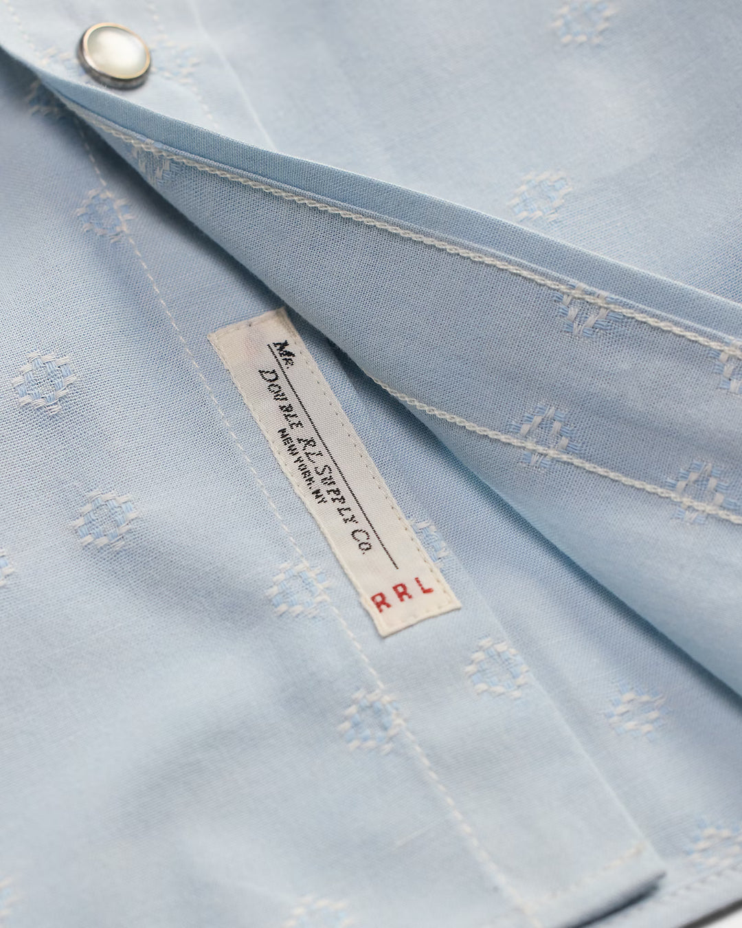 Close-up of a light blue fabric with a brand label on a matching background